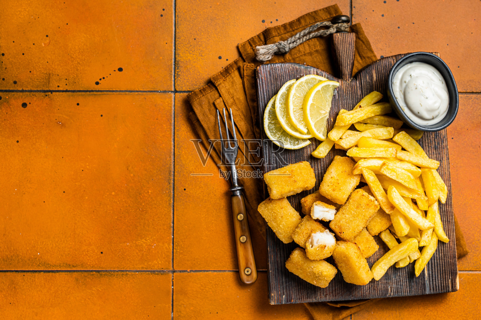 炸鱼薯条英国快餐，炸鱼条和薯条放在木板上。橙色背景。前视图。本空间照片摄影图片