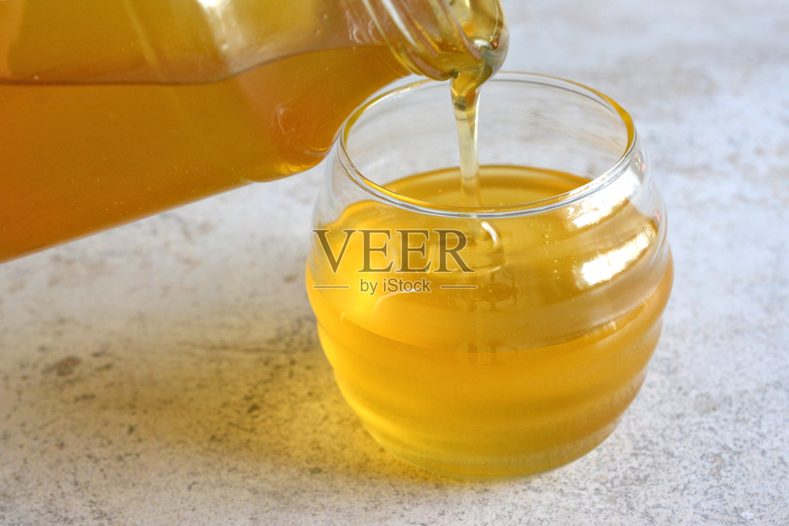 将蜂蜜倒入杯中，靠近蜂蜜照片摄影图片