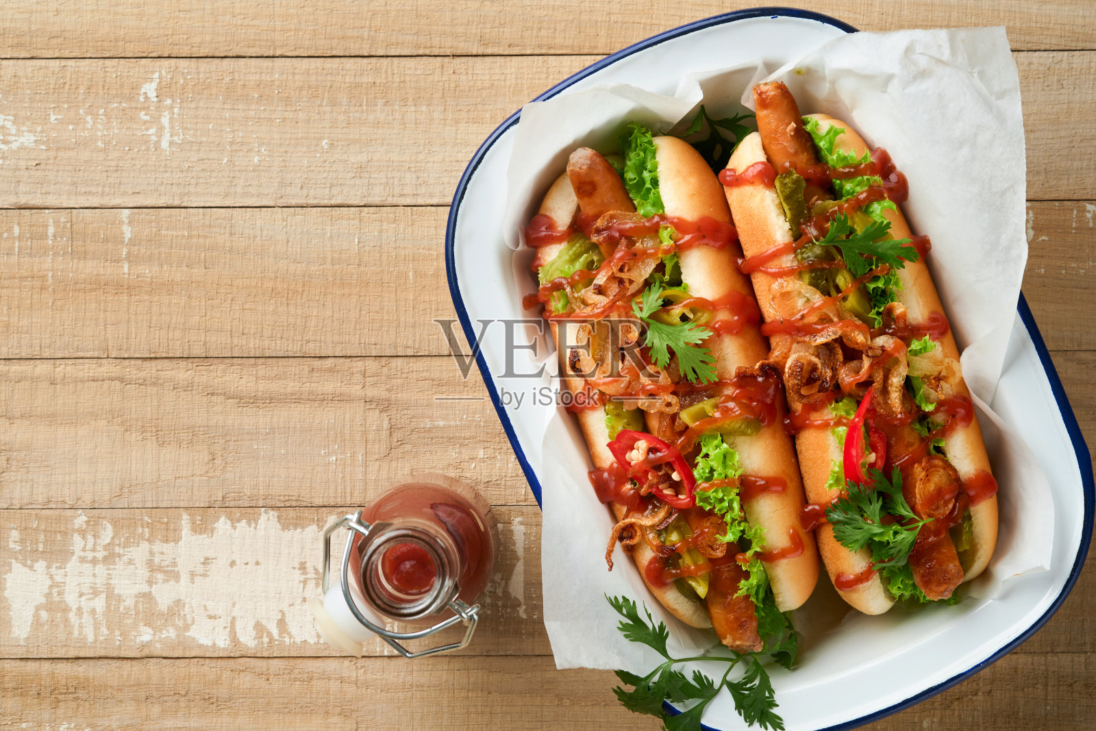 美味的烤热狗配上腌黄瓜，辣椒，焦糖洋葱和番茄酱，芥末在旧木制背景纸上。自制美国热狗庆祝独立日。照片摄影图片