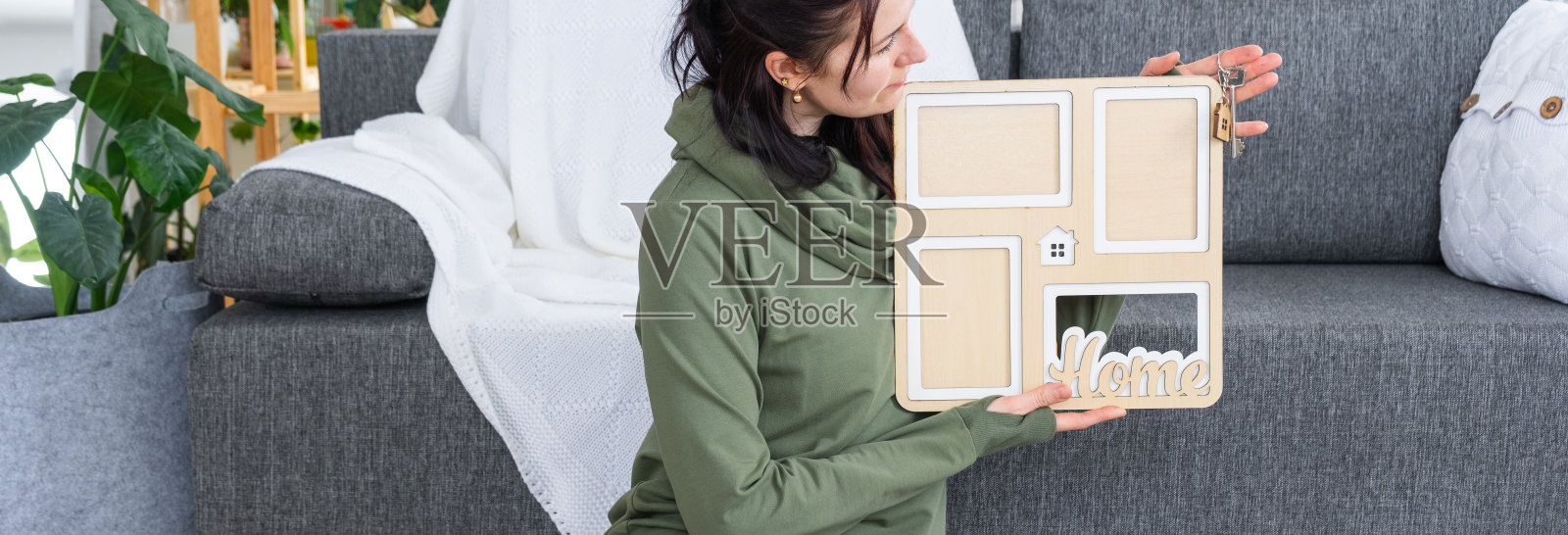 家里快乐的女人手里拿着家里图形模板和钥匙的相框。梦想之家项目，房产购买，保险，抵押，租赁，预订照片摄影图片