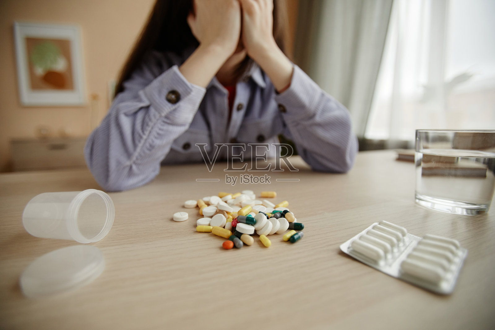 一堆药片和药片的特写，年轻女子在背后哭泣照片摄影图片