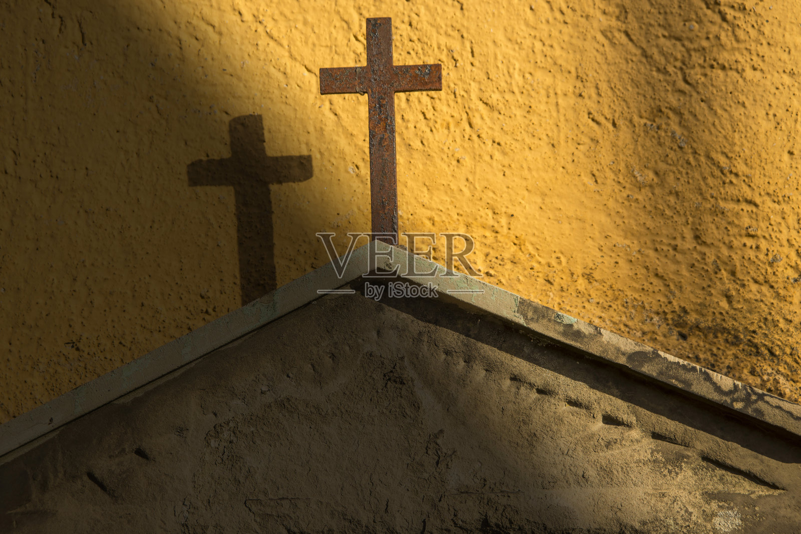 墓碑上的十字架在黄色的墙上照片摄影图片