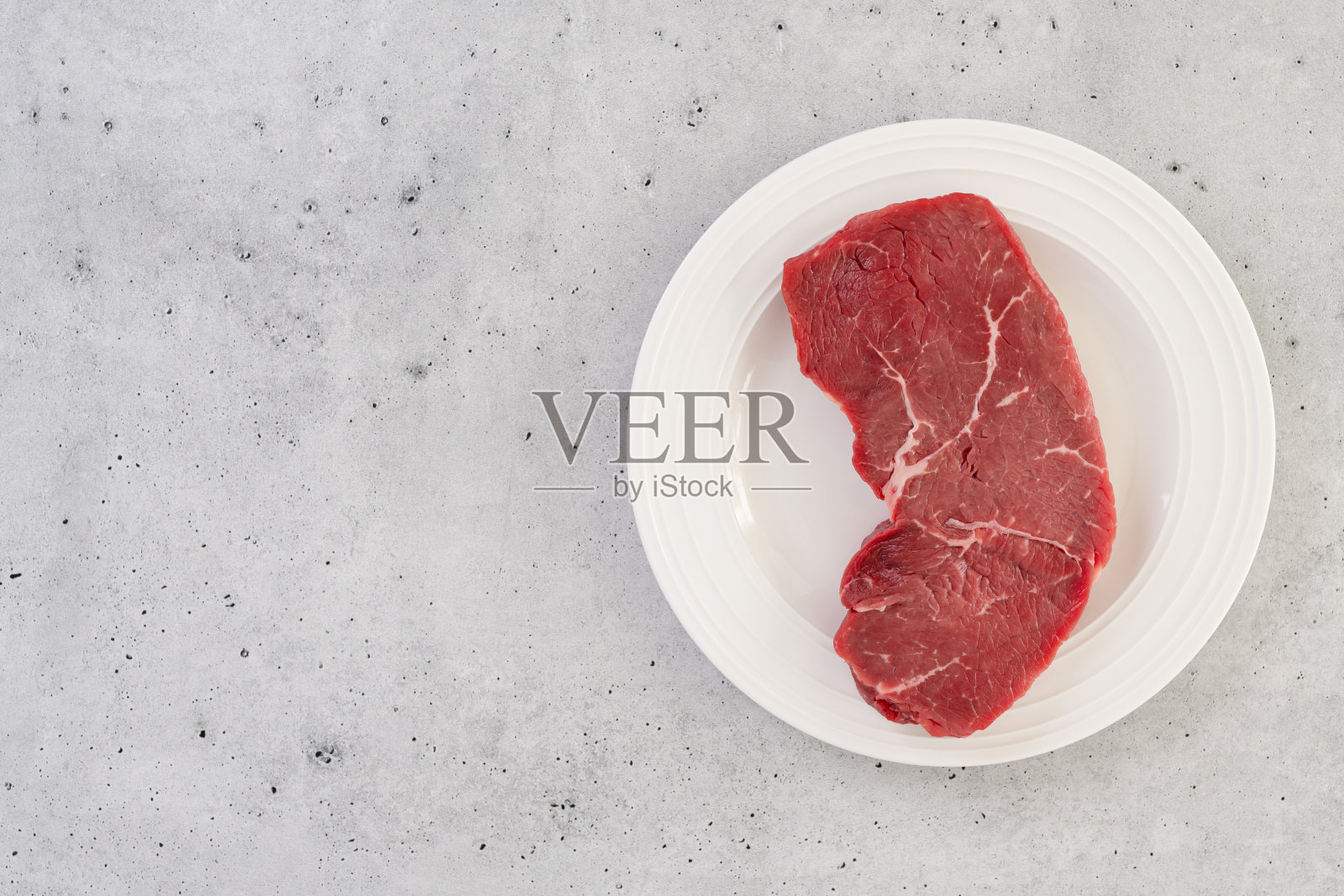 白色盘子里的生牛排，从上方特写照片摄影图片