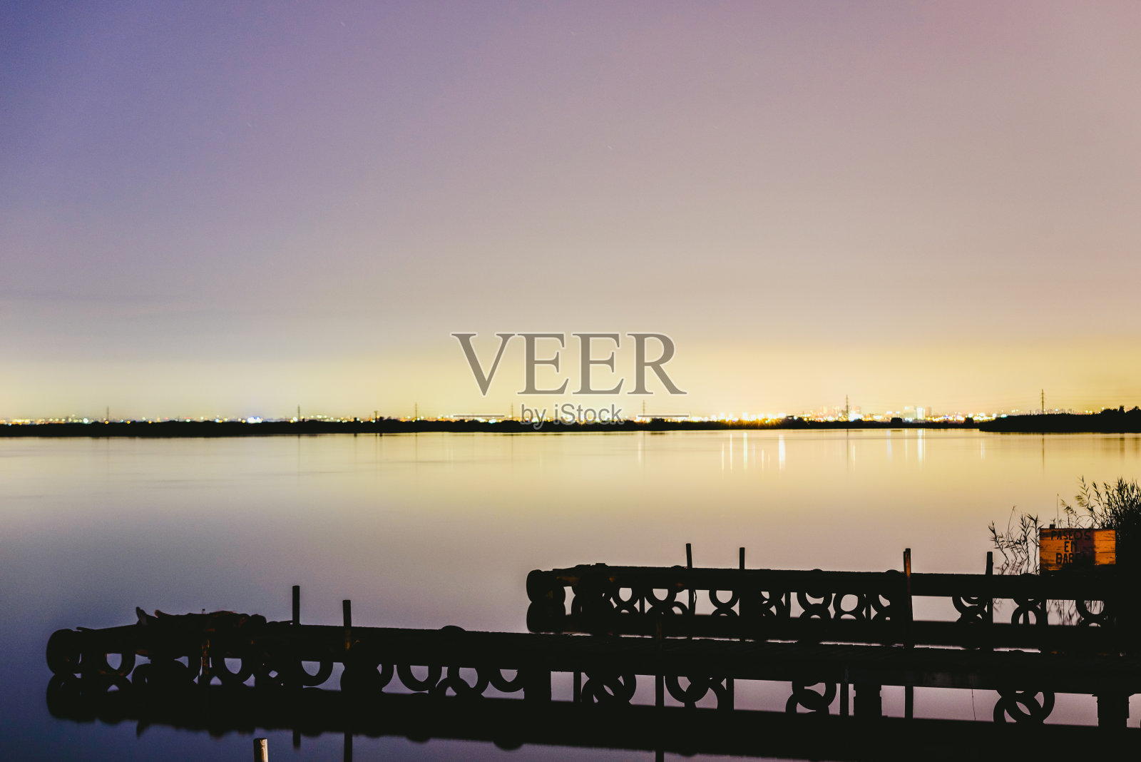 日落时分，码头在湖面上，平静的水面和令人放松的灯光反射。照片摄影图片