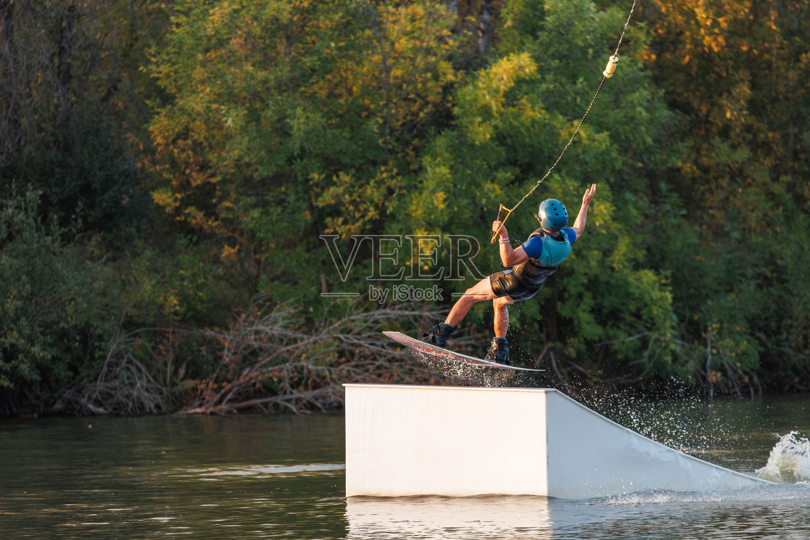 运动员从跳板上跳下来。日落时的滑水板公园。一个人在棋盘上耍把戏照片摄影图片