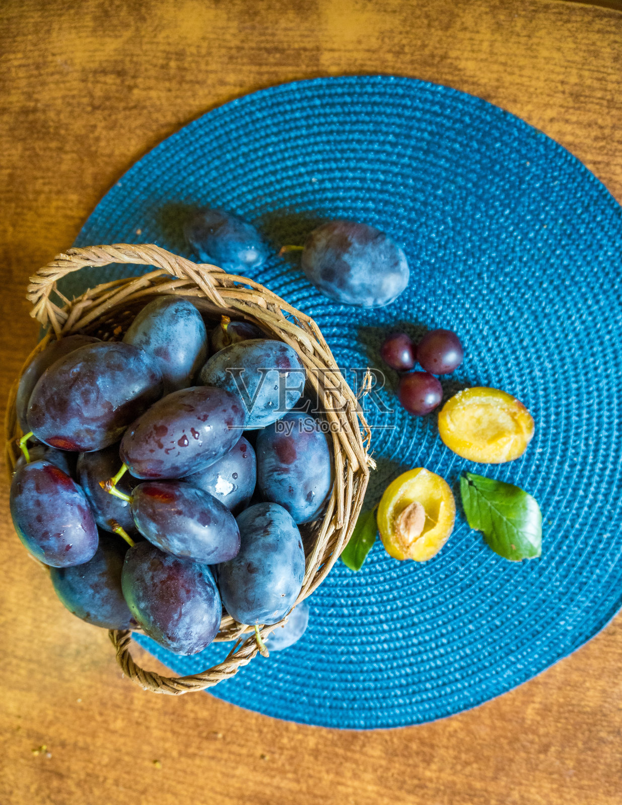 木质背景上一篮新鲜成熟的李子照片摄影图片