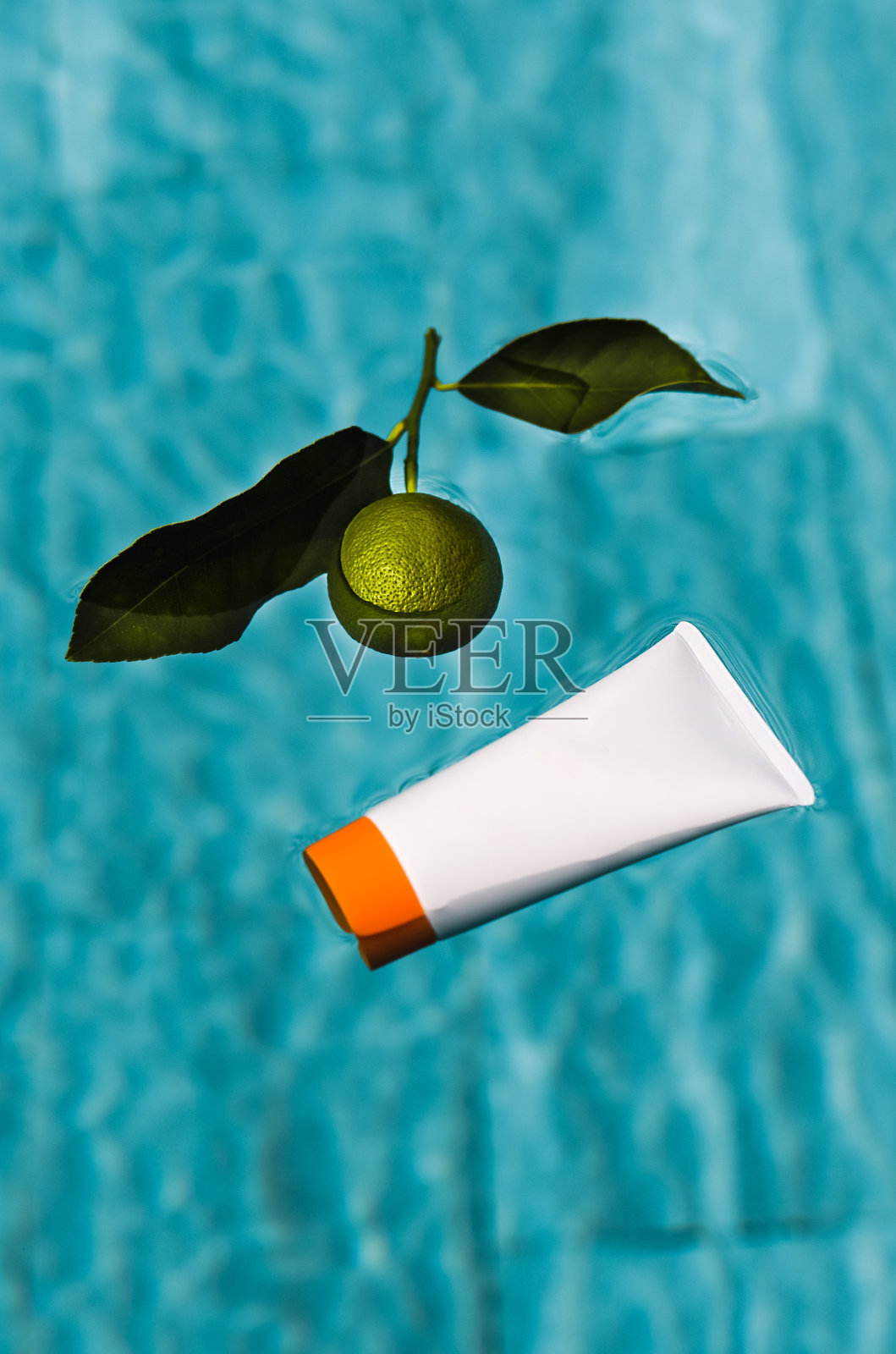 美容产品管包装漂浮在游泳池水面与酸橙水果照片摄影图片