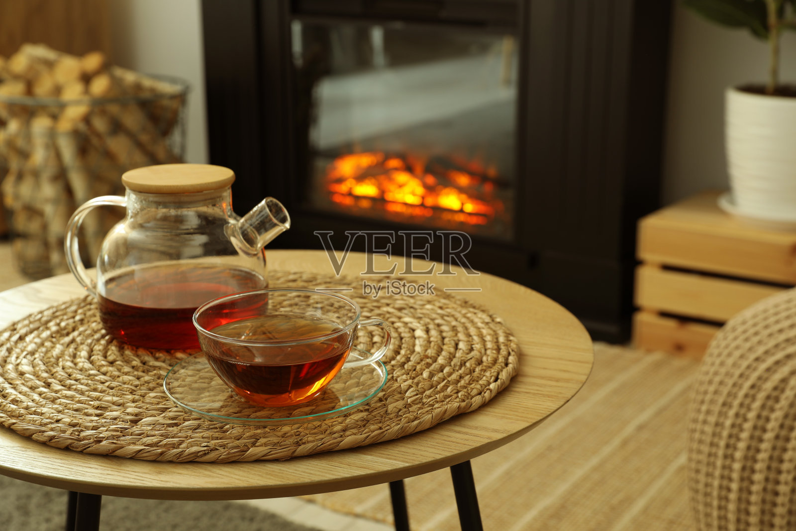 茶壶和一杯饮料在咖啡桌上靠近时尚的壁炉在舒适的客厅。室内设计照片摄影图片