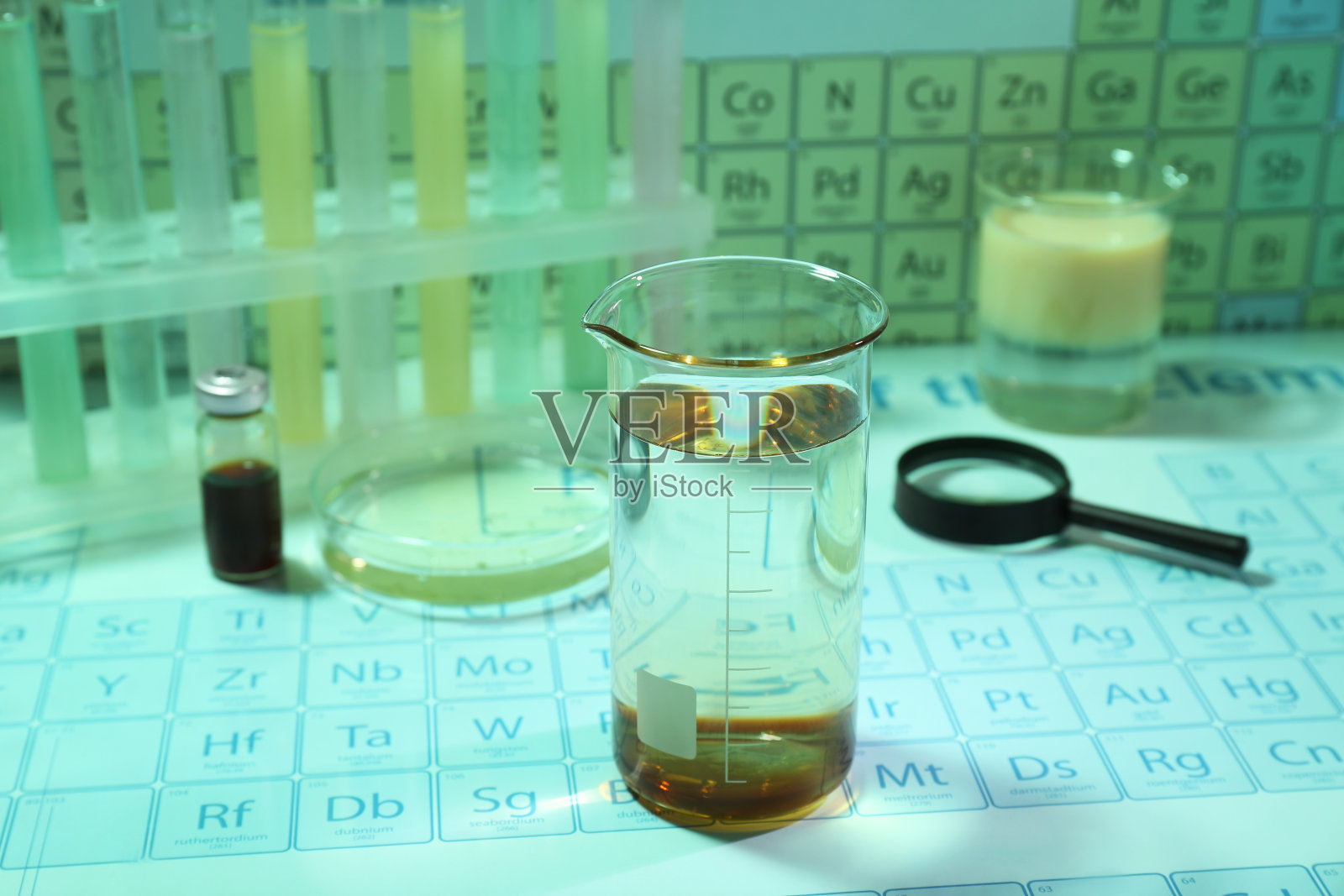 烧杯用液体和化学元素周期表上的实验室设备。浅绿色色调效果照片摄影图片