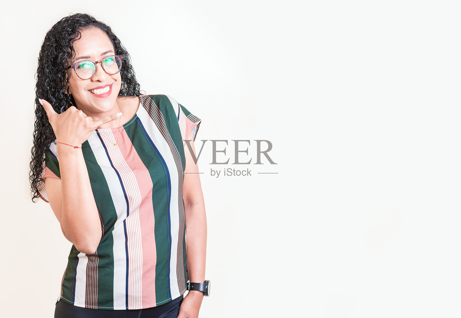 戴眼镜的拉丁女人用手指分开的手势打电话。快乐的女孩戴着眼镜打手势叫我用手隔离照片摄影图片