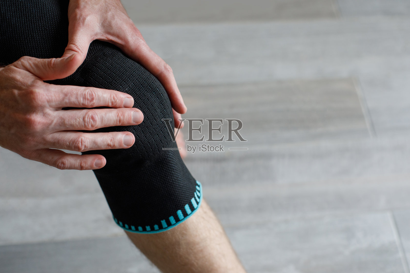 穿着护膝打底裤的男子在灰色背景下运动照片摄影图片