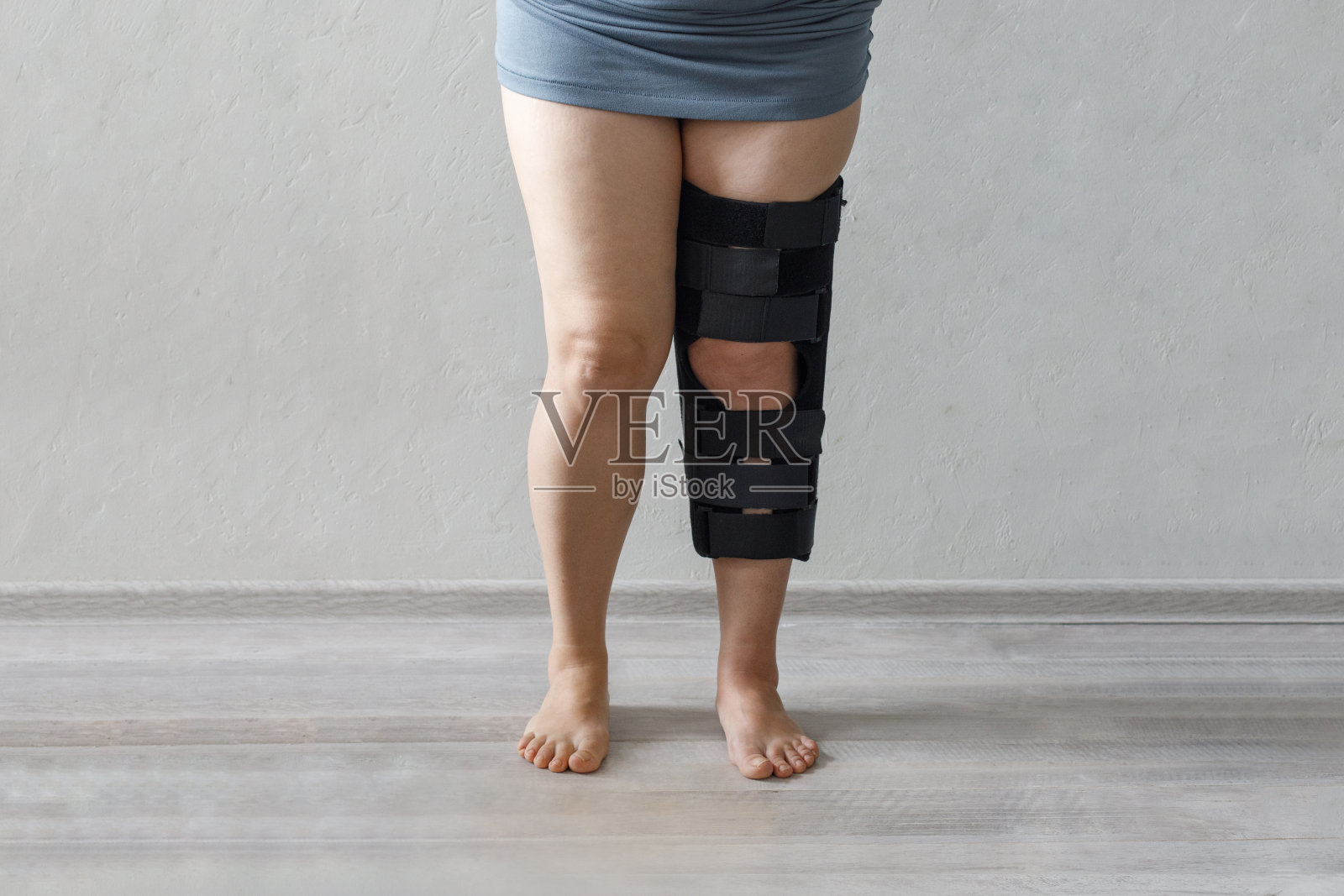 黑色医用护膝，在灰色背景的女性膝盖上有固定物照片摄影图片