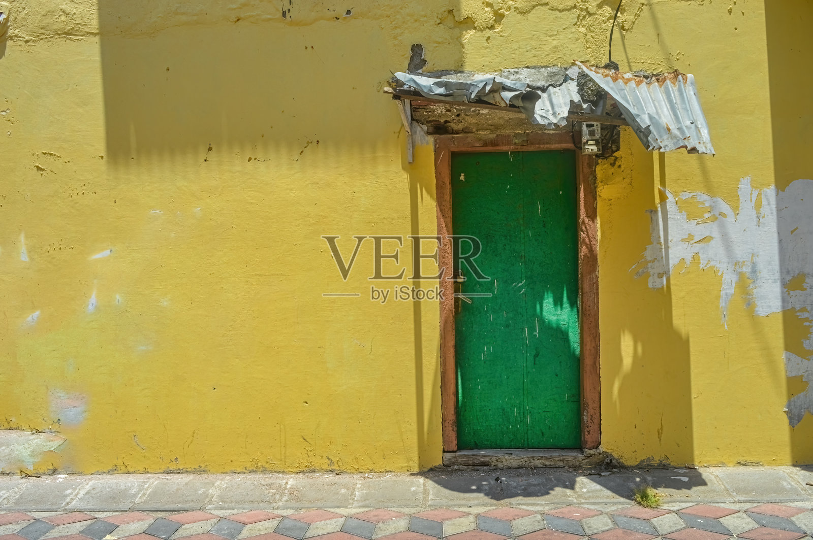 一扇绿色的木门，黄色的墙壁显示出老房子上一些剥落的油漆照片摄影图片