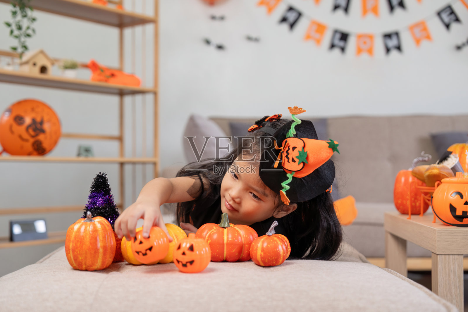 可爱的小女孩拿着南瓜气球。快乐的家庭为万圣节做准备照片摄影图片