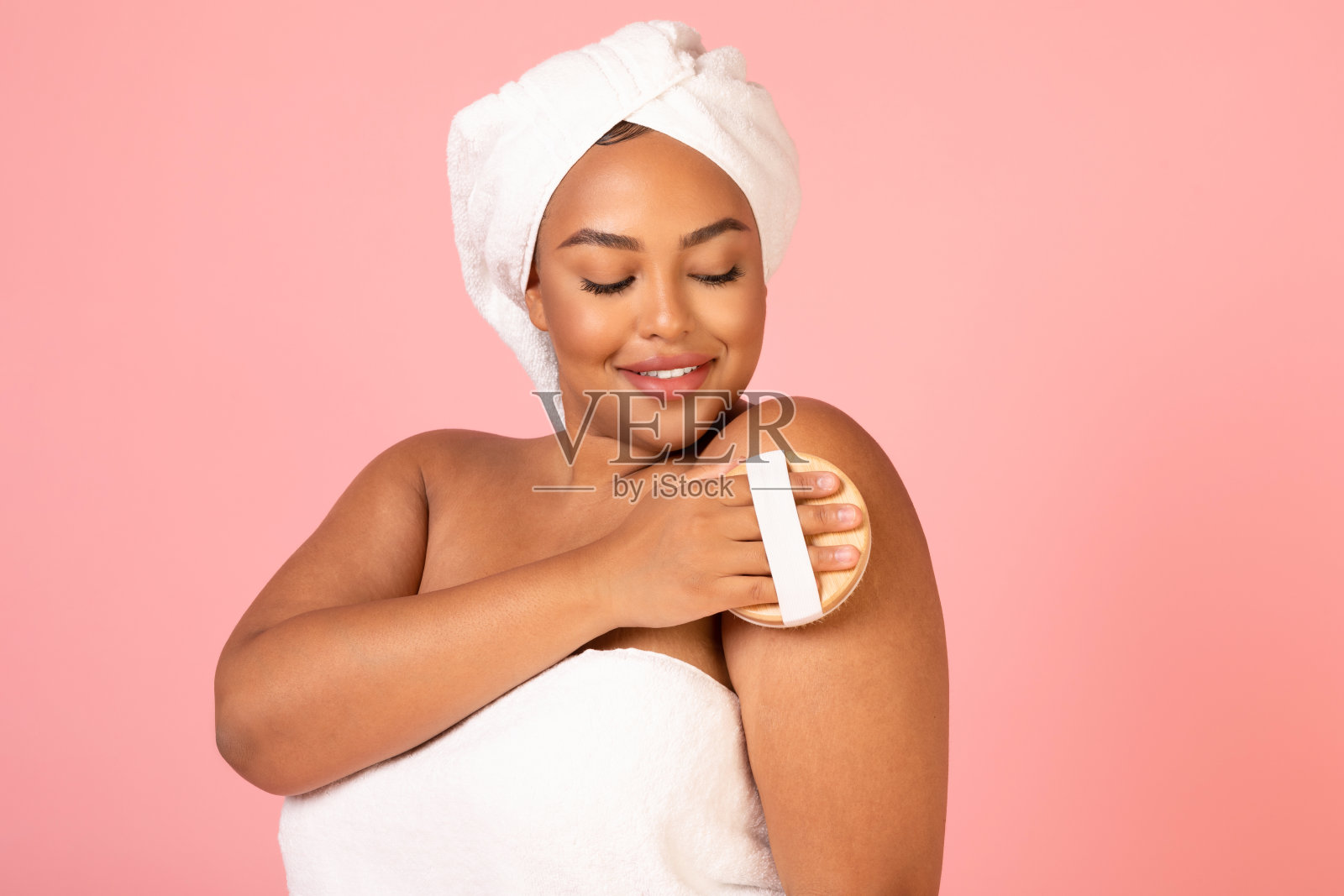 非洲女士按摩身体与干刷粉红色的背景照片摄影图片