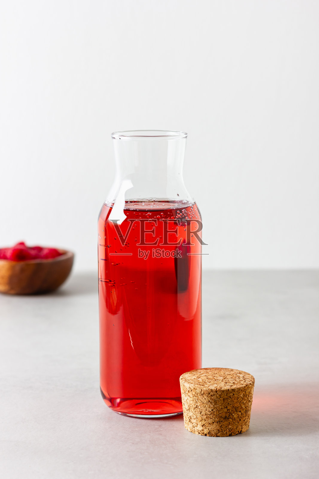 覆盆子饮料在玻璃瓶子上的浅色背景。照片摄影图片