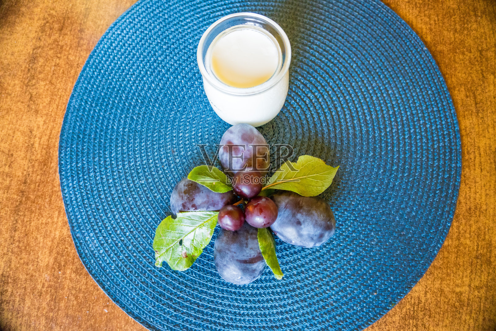 在木桌上，用玻璃杯盛着甜甜的自制酸奶和新鲜的李子片照片摄影图片