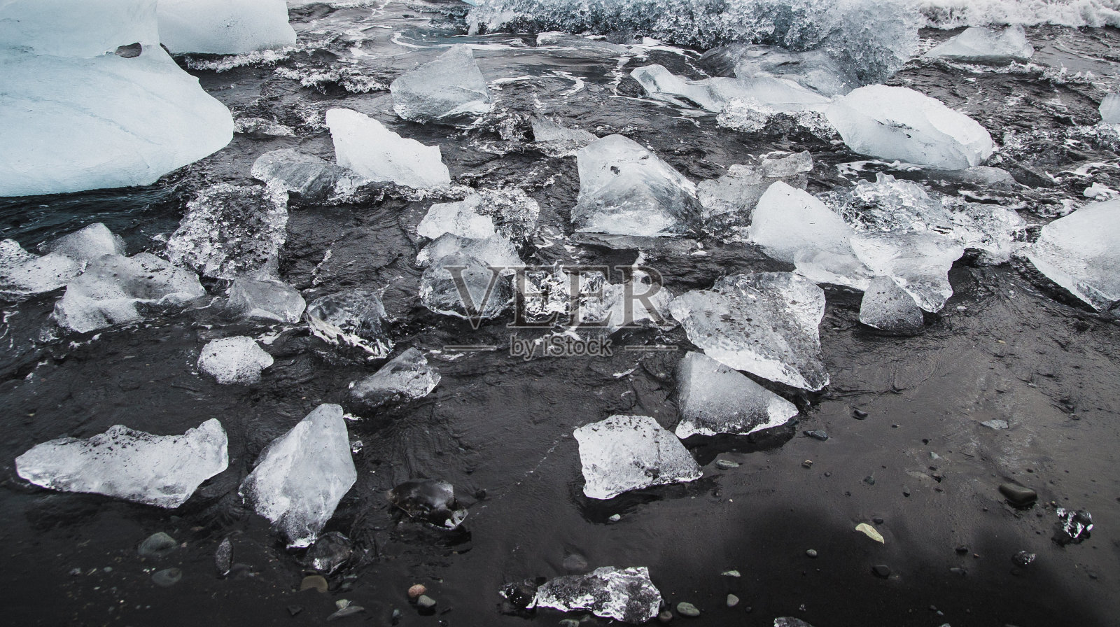在冰岛海滩的海岸上，巨大的冰块从冰山上脱落。照片摄影图片