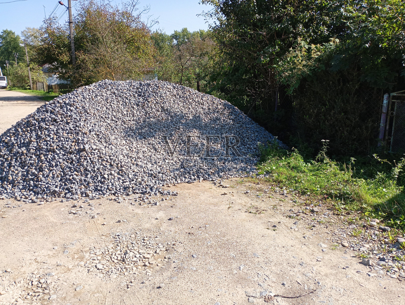 为了修复一条乡间土路，将在路边倒砾石。道路两旁的建筑材料是用来填坑洞的。照片摄影图片