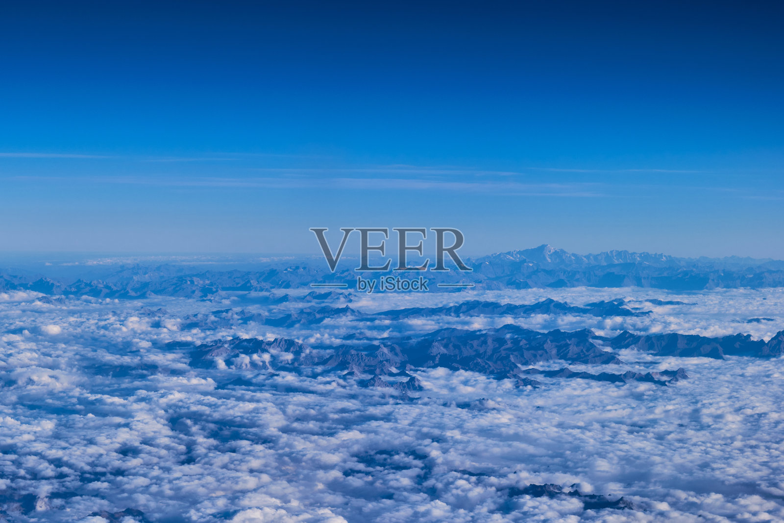 从飞机上透过云层看到的山峰照片摄影图片