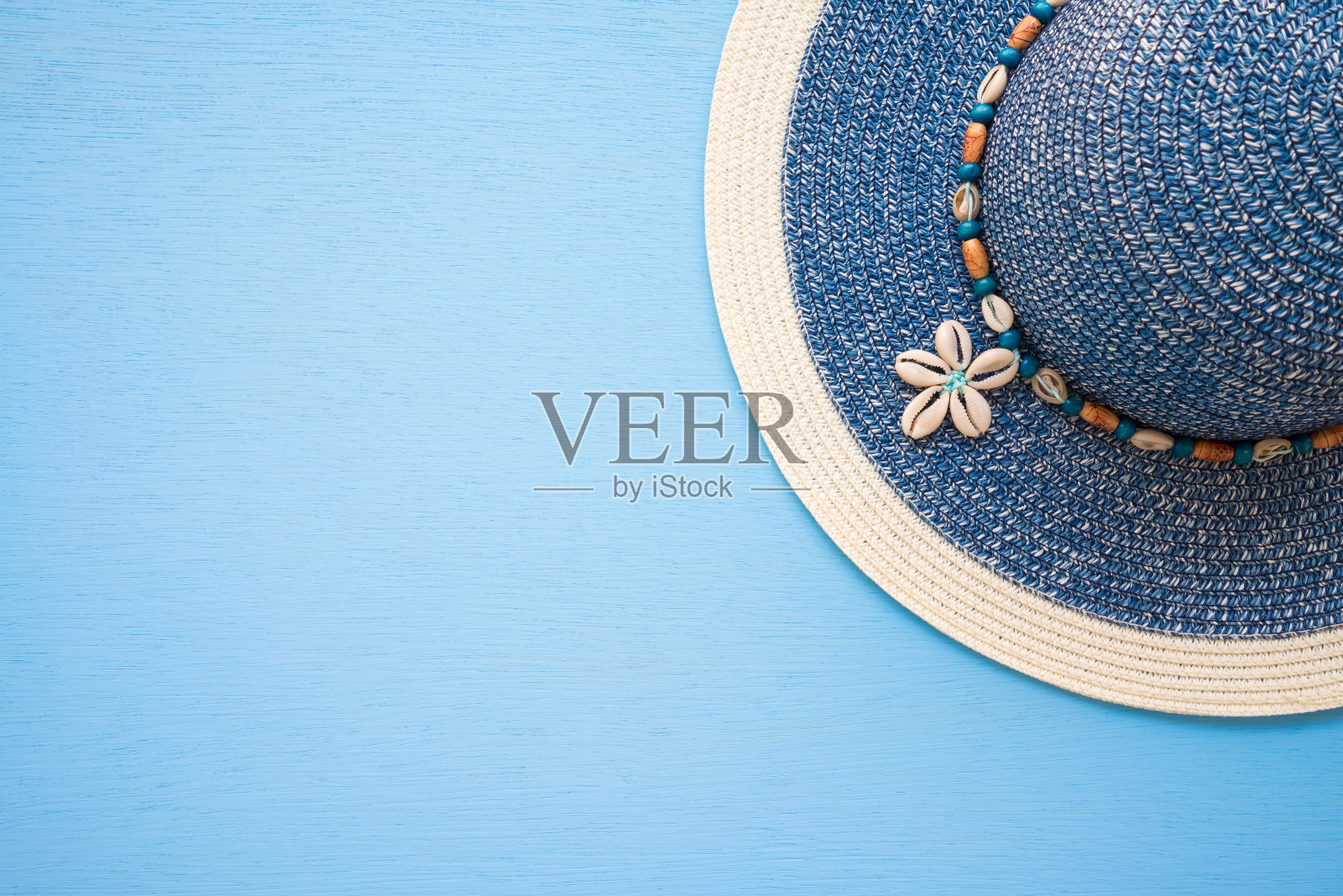 蓝色女士沙滩帽上的蓝色木制背景与复制空间。照片摄影图片