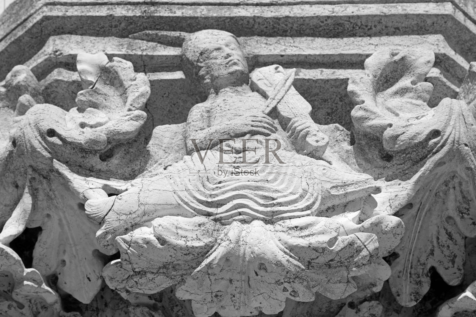 意大利威尼斯公爵宫的一尊雕像上，一名男子在海豚上演奏中世纪时期使用的弓弦乐器vielle照片摄影图片