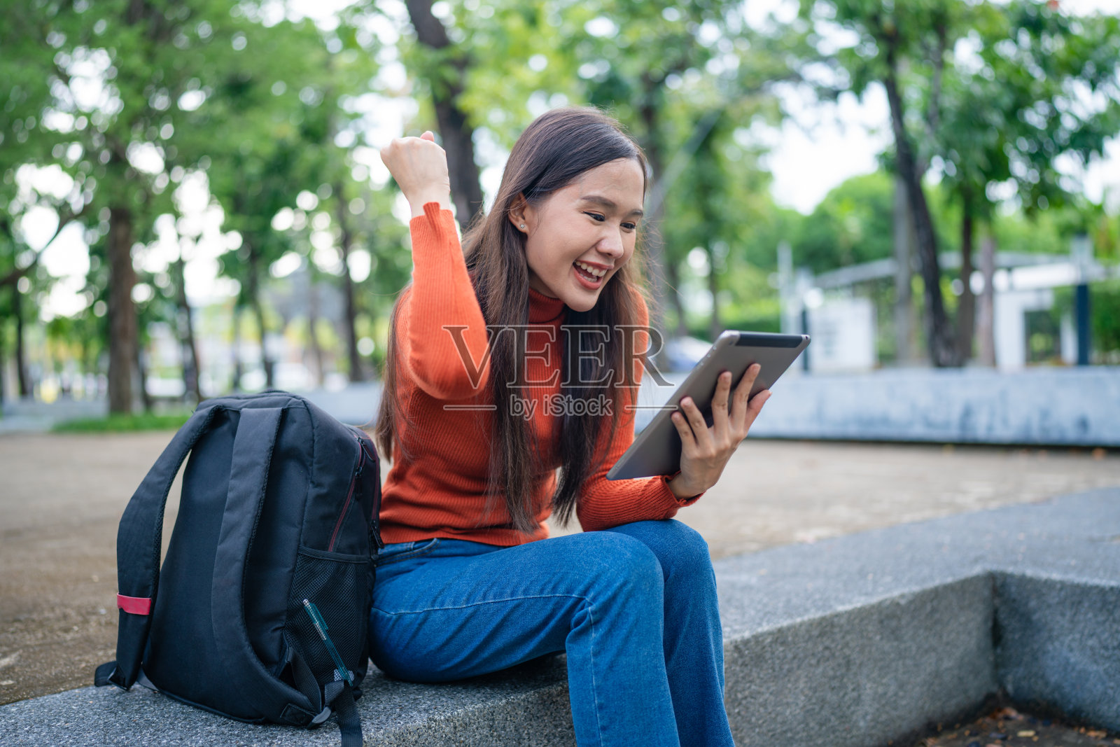 年轻微笑优雅的亚洲忙碌妇女坐在使用平板电脑平台的应用程序。照片摄影图片