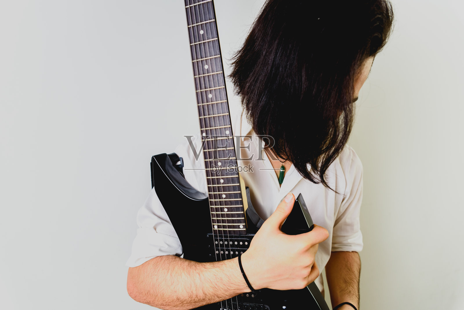 吉他手拿着电吉他摆姿势，白色背景。照片摄影图片