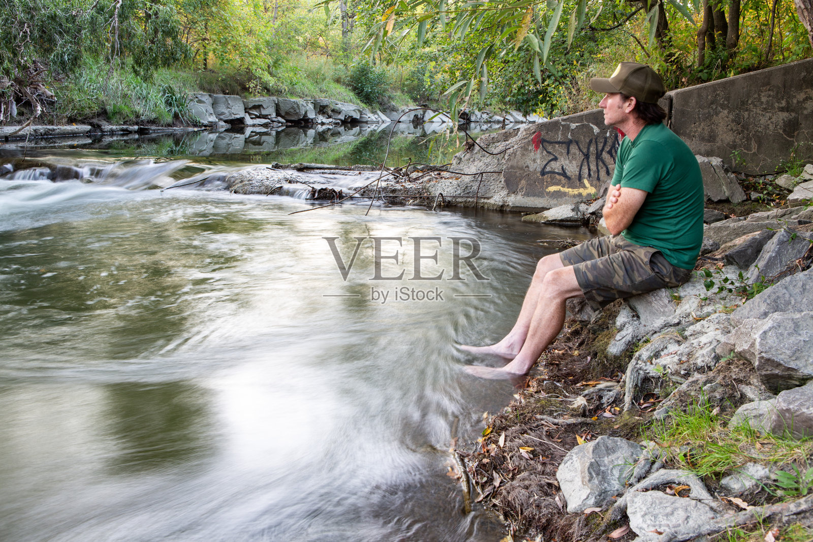 穿着绿色t恤的人坐在河床边照片摄影图片