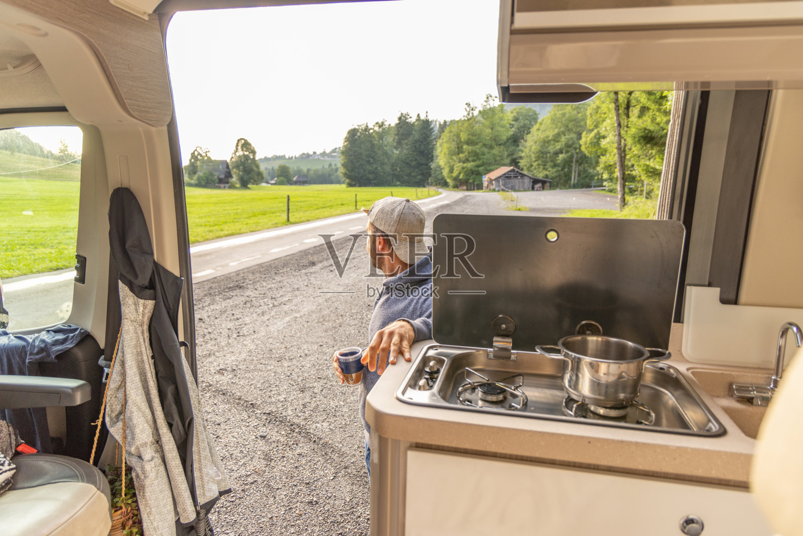 一名男子一边喝着茶，一边享受着他租来的露营车照片摄影图片