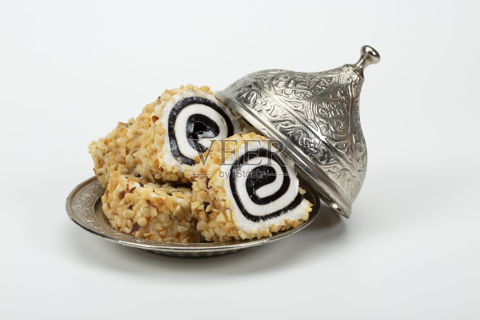 美味的土耳其软糖(Lokum)和坚果放在传统雕刻图案的金属盘子上。照片摄影图片