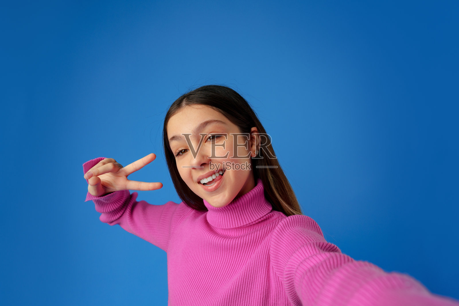 一个微笑的少女在蓝色背景下自拍照片摄影图片