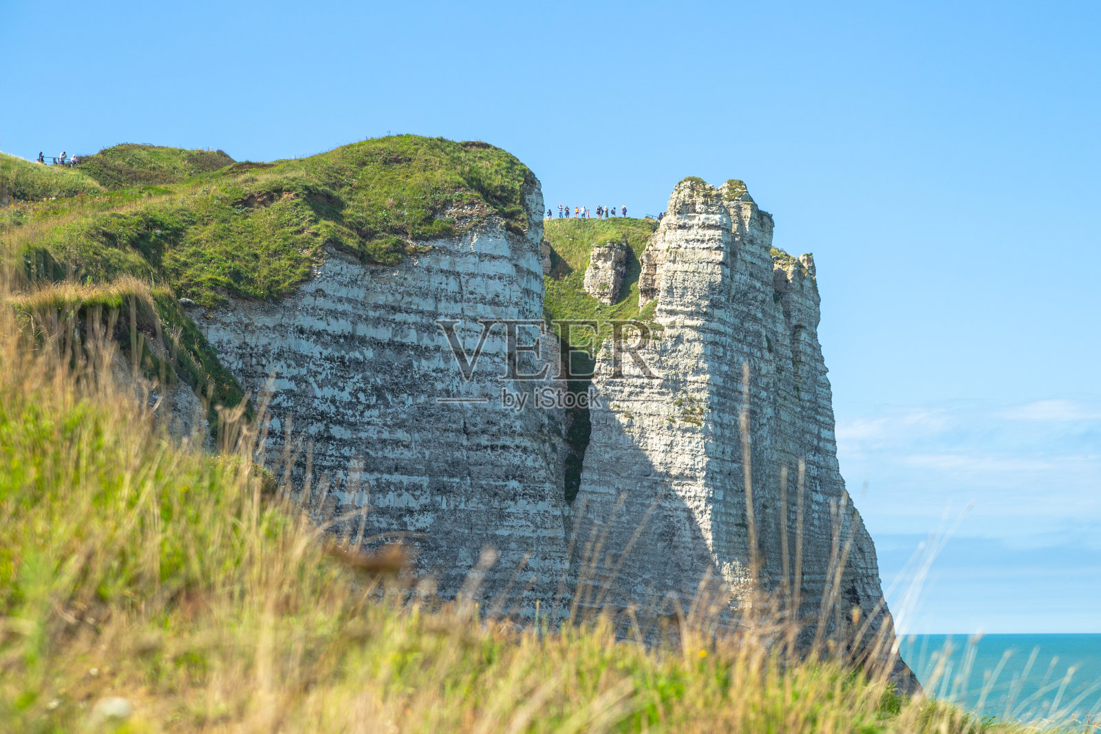 仰望天使的白色高耸的海崖与草覆盖在Étretat的顶部照片摄影图片