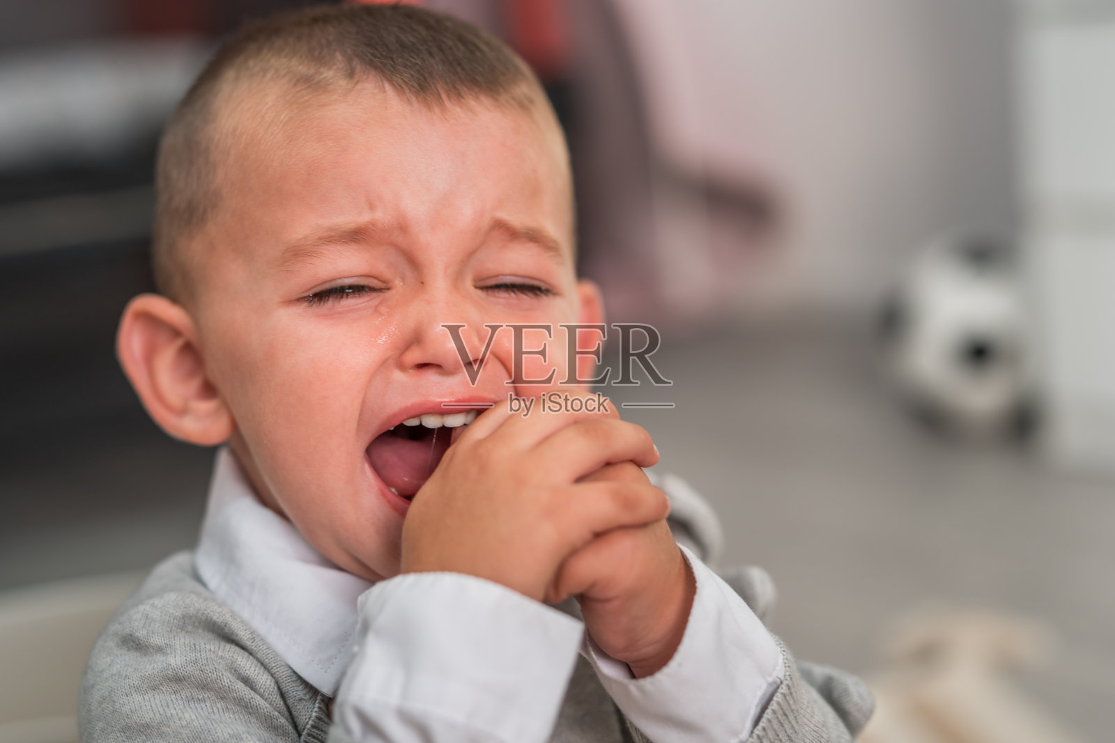 一个蹒跚学步的男孩坐在家里的地板上哭照片摄影图片