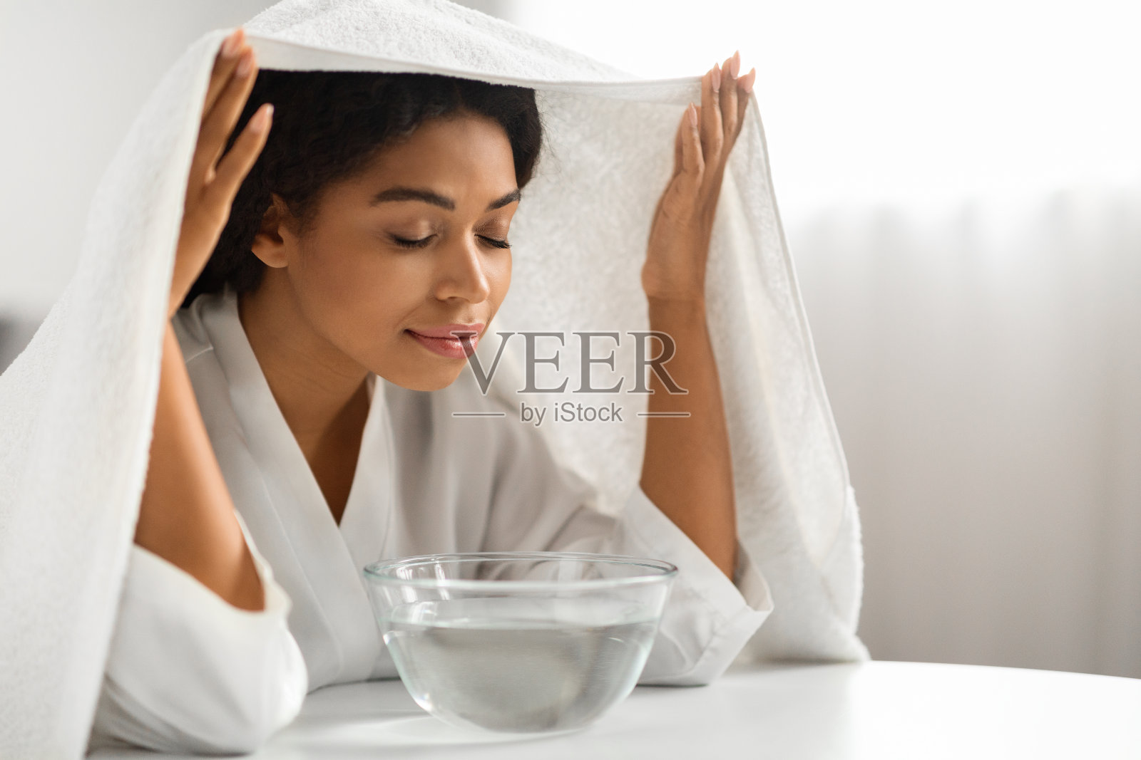 美黑客。年轻的黑人妇女在家里吸入热水的蒸汽照片摄影图片