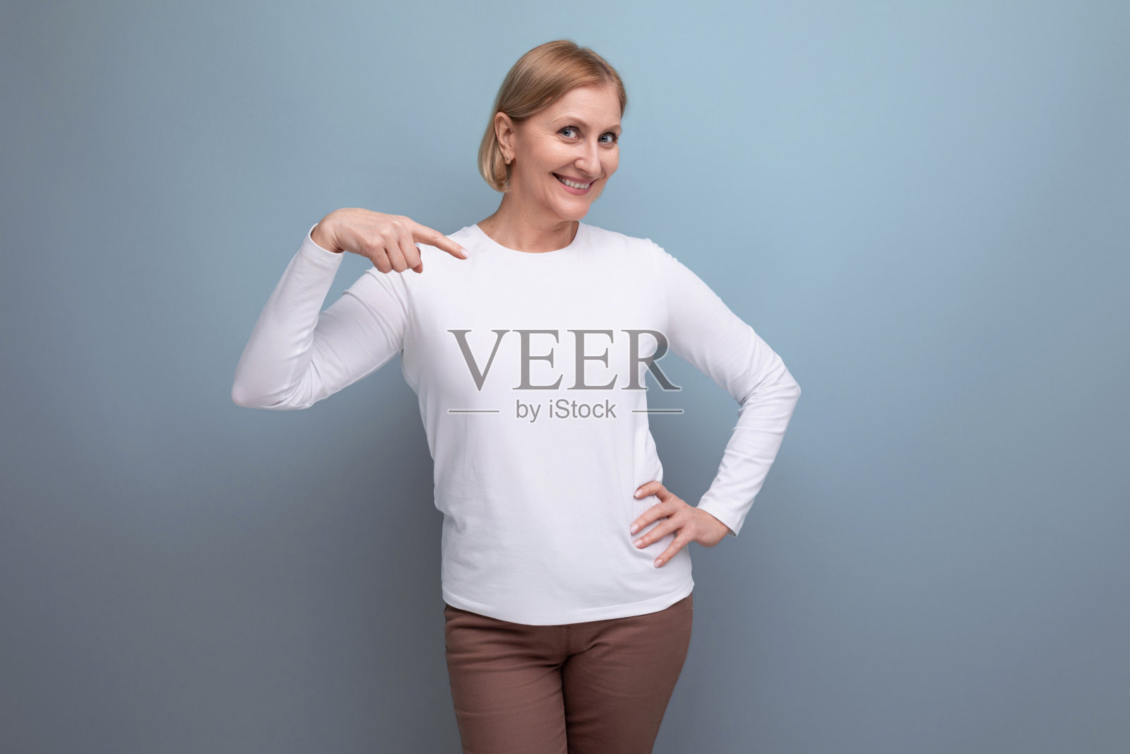 50多岁的金发女子身穿白色毛衣，在带有复印空间的演播室里报道新闻照片摄影图片