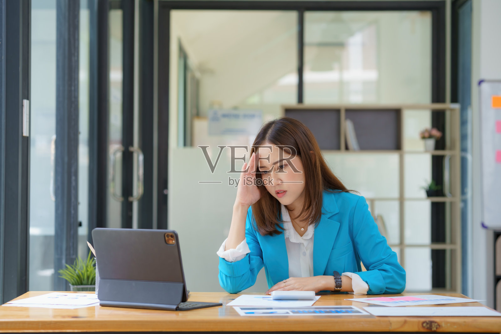 一个亚洲女商人的肖像，坐在电脑前努力工作，在工作场所的桌子上有很多文件，很晚才认真行动，努力工作，太晚的观念。照片摄影图片
