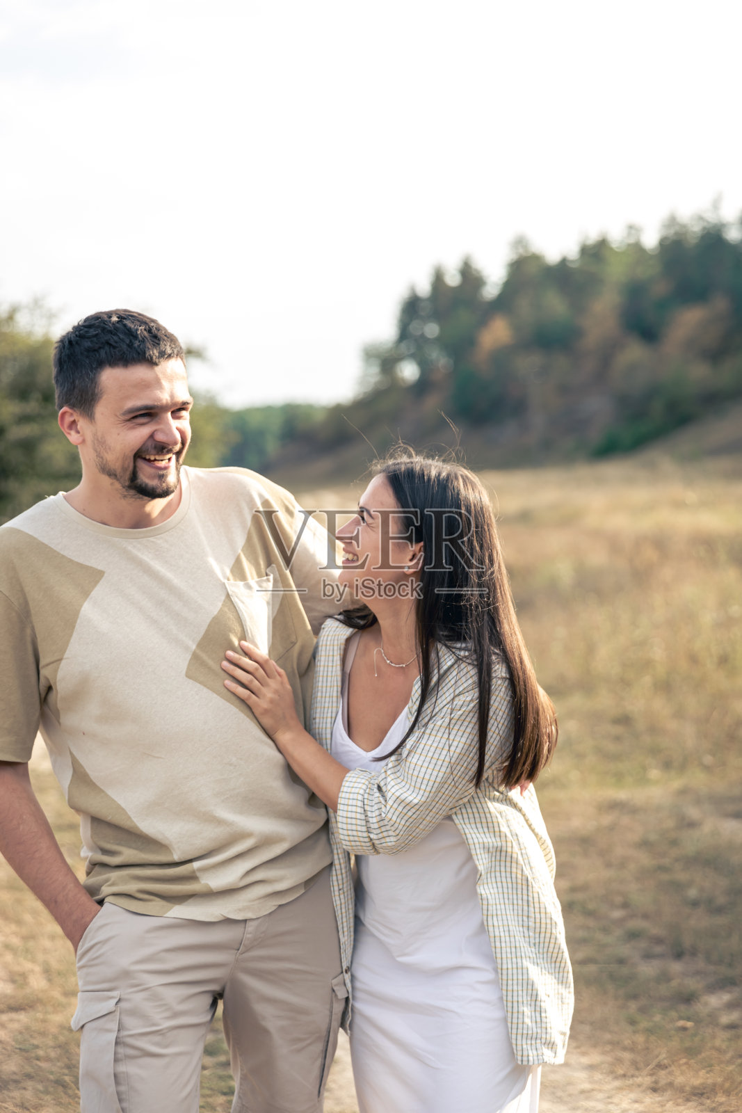 一个男人和一个女人走在田野里，一对幸福的夫妇。照片摄影图片