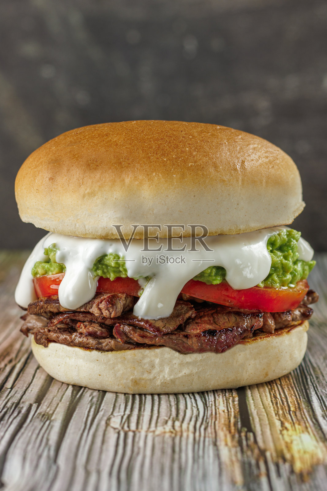 智利流行的意大利烤肉三明治，圆形面包，牛肉，番茄和鳄梨，木桌上，竖版。典型的智利美食概念照片摄影图片