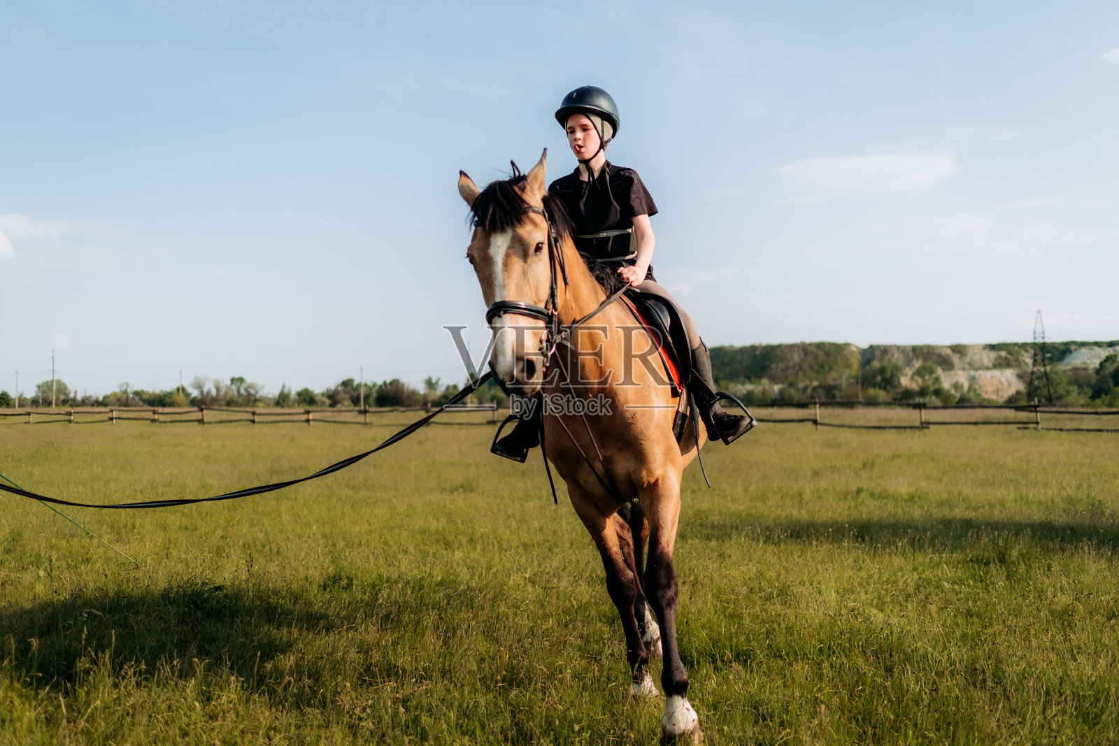 一个戴着头盔的少年在夏天学习骑马，教练教孩子马术。照片摄影图片