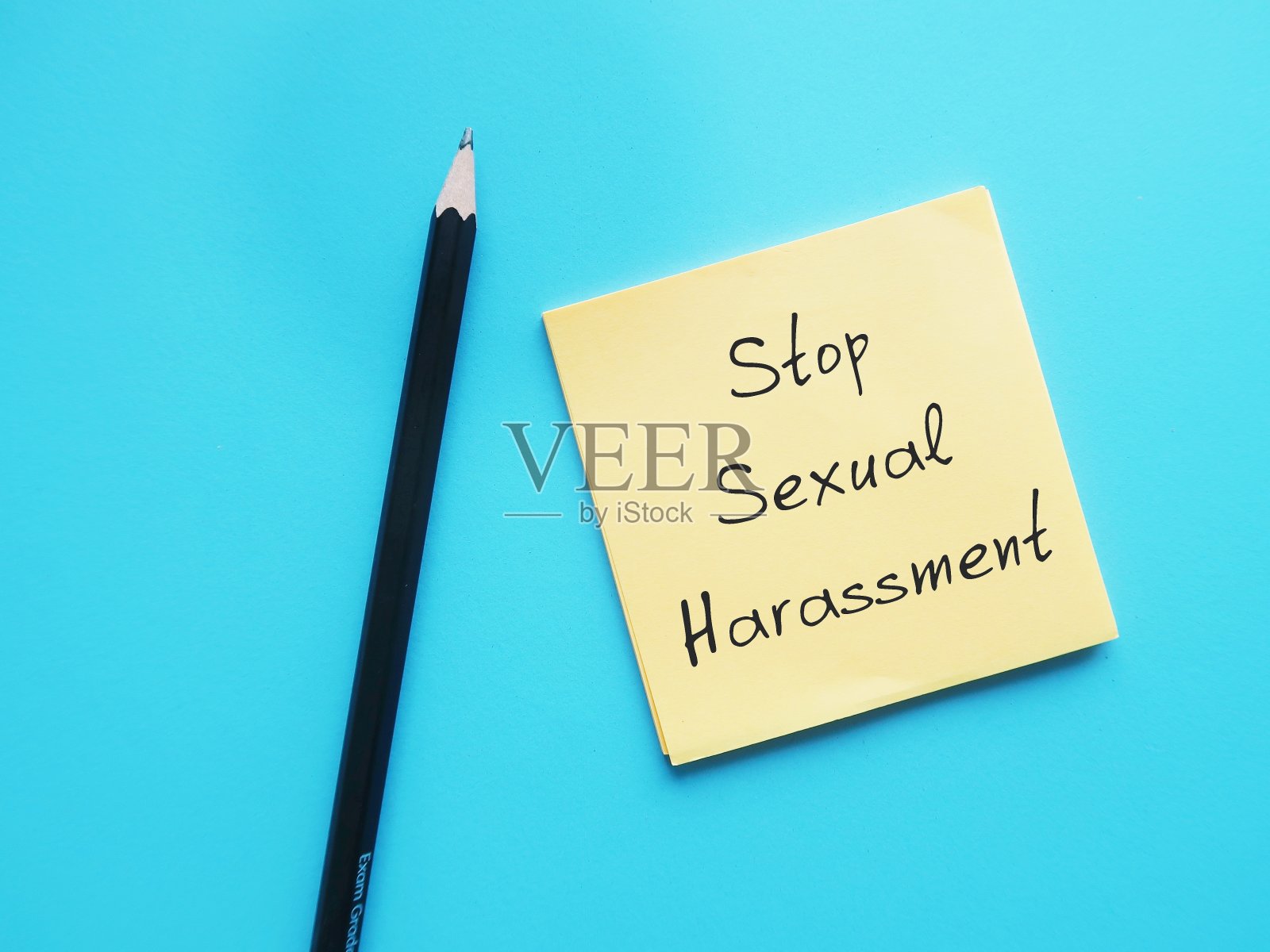 铅笔在蓝色背景的办公记事本上手写文字“停止性骚扰”，以阻止不必要的持续攻击行为，这些行为会使员工感到受到威胁或冒犯，并在工作场所造成情感或精神上的痛苦照片摄影图片