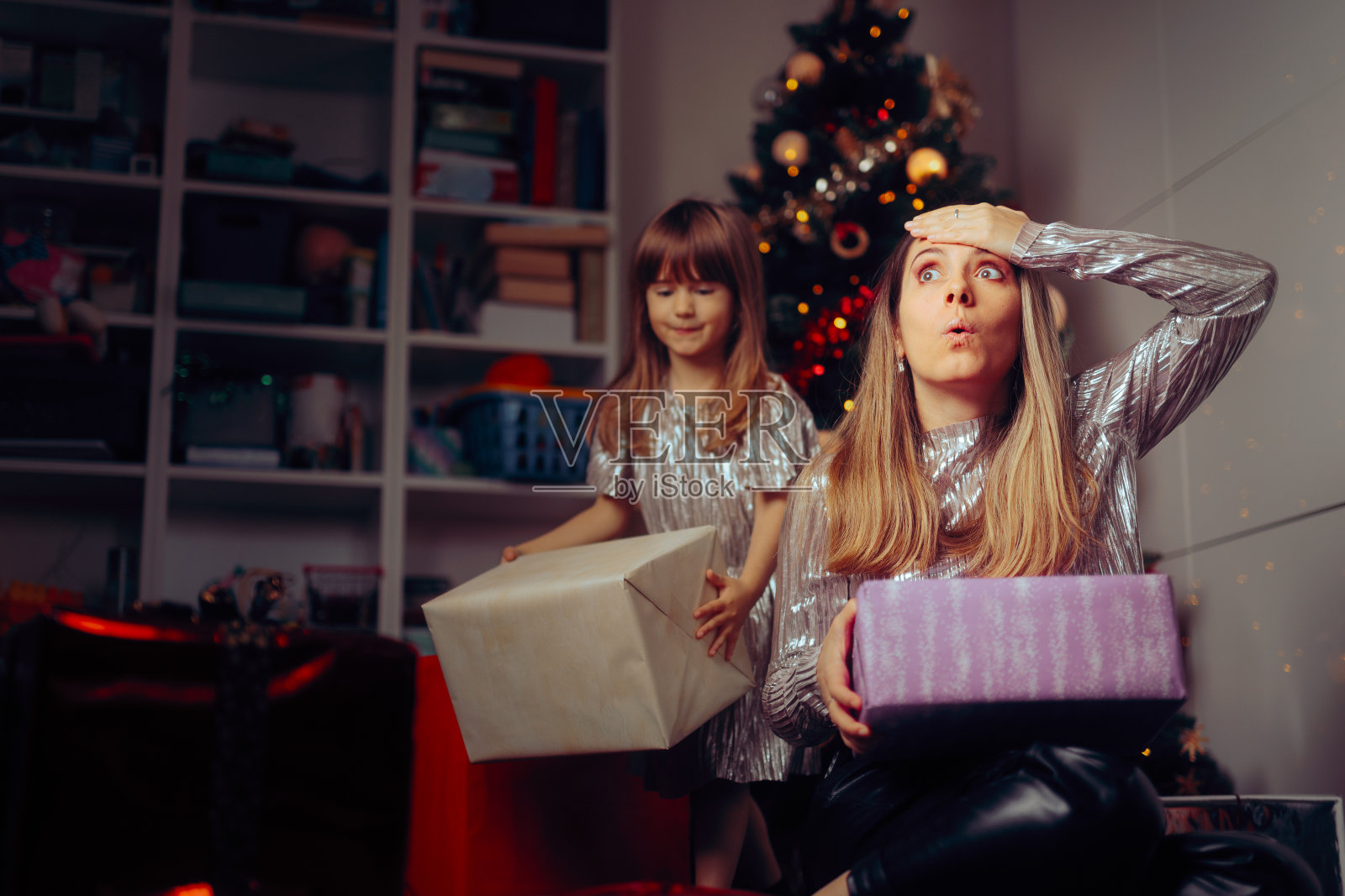 不知所措的妈妈和女儿在圣诞树下整理礼物照片摄影图片