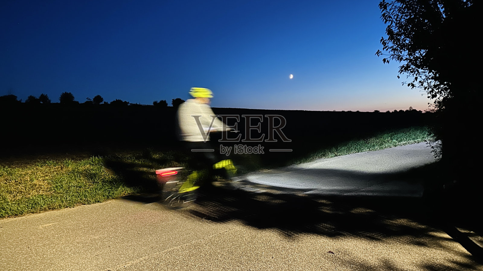 月光下的蓝天下，骑自行车的人的夜景照片摄影图片