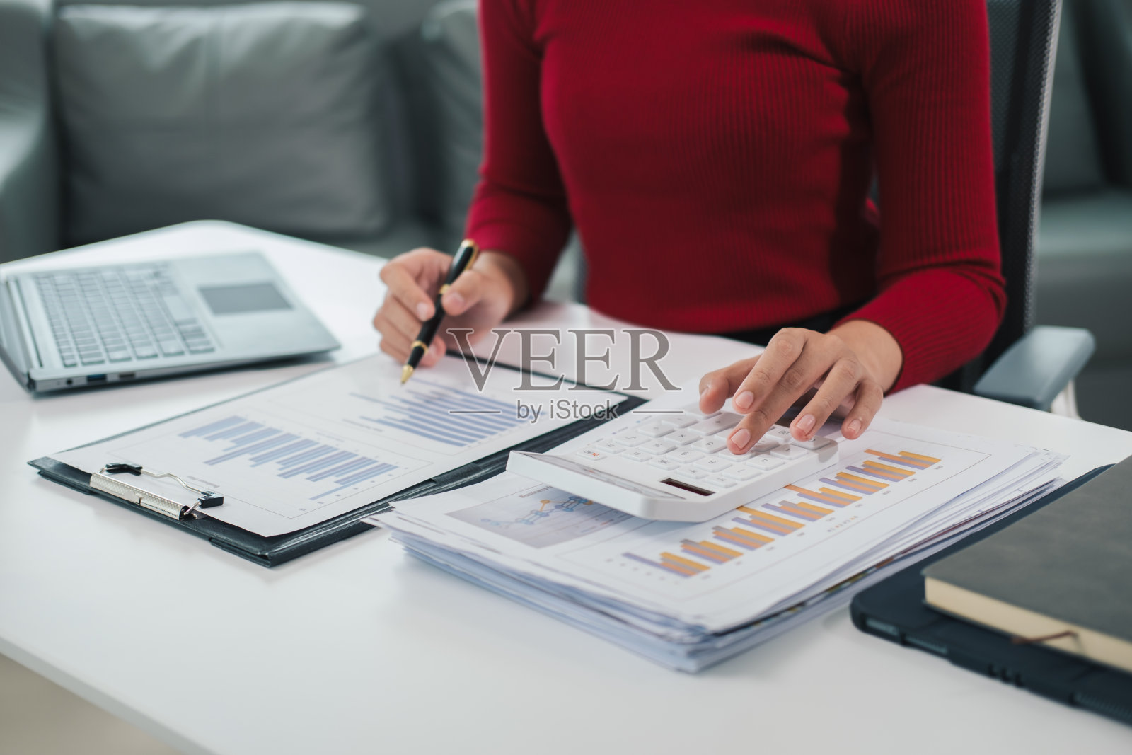 商人用计算器计算公司财务文件上的数字，他正在分析历史财务数据，以计划如何发展公司。金融的概念。照片摄影图片