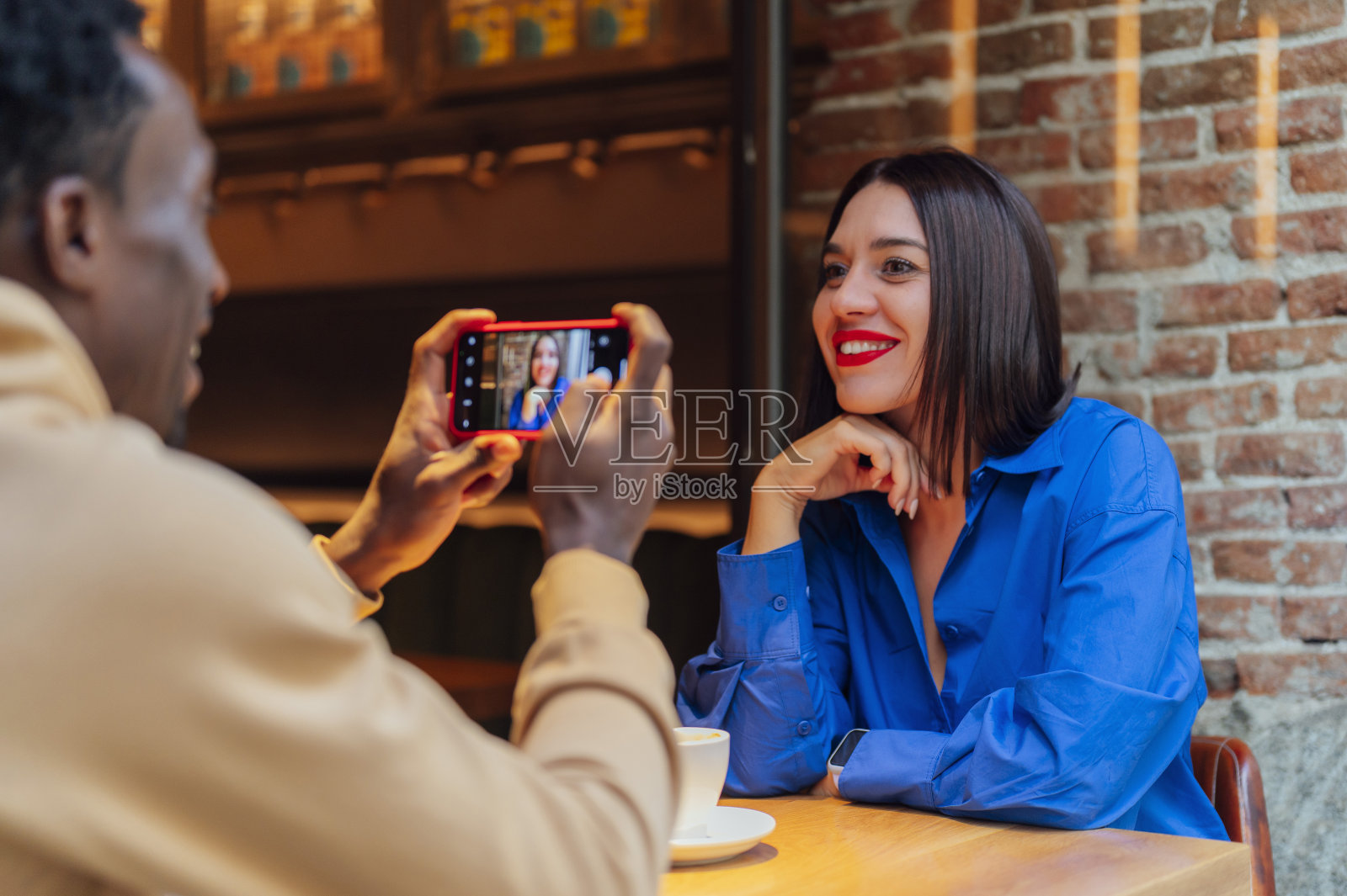 一个年轻人和他的朋友在咖啡馆喝咖啡自拍。年轻的朋友坐在一起在咖啡馆自拍。照片摄影图片