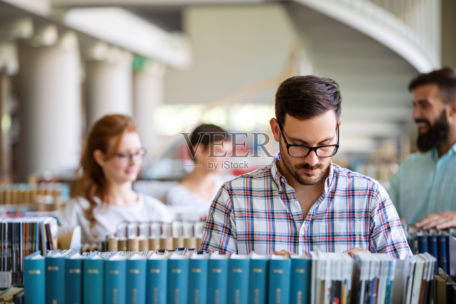 快乐的大学生在图书馆读书。大学里的多种族人群照片摄影图片
