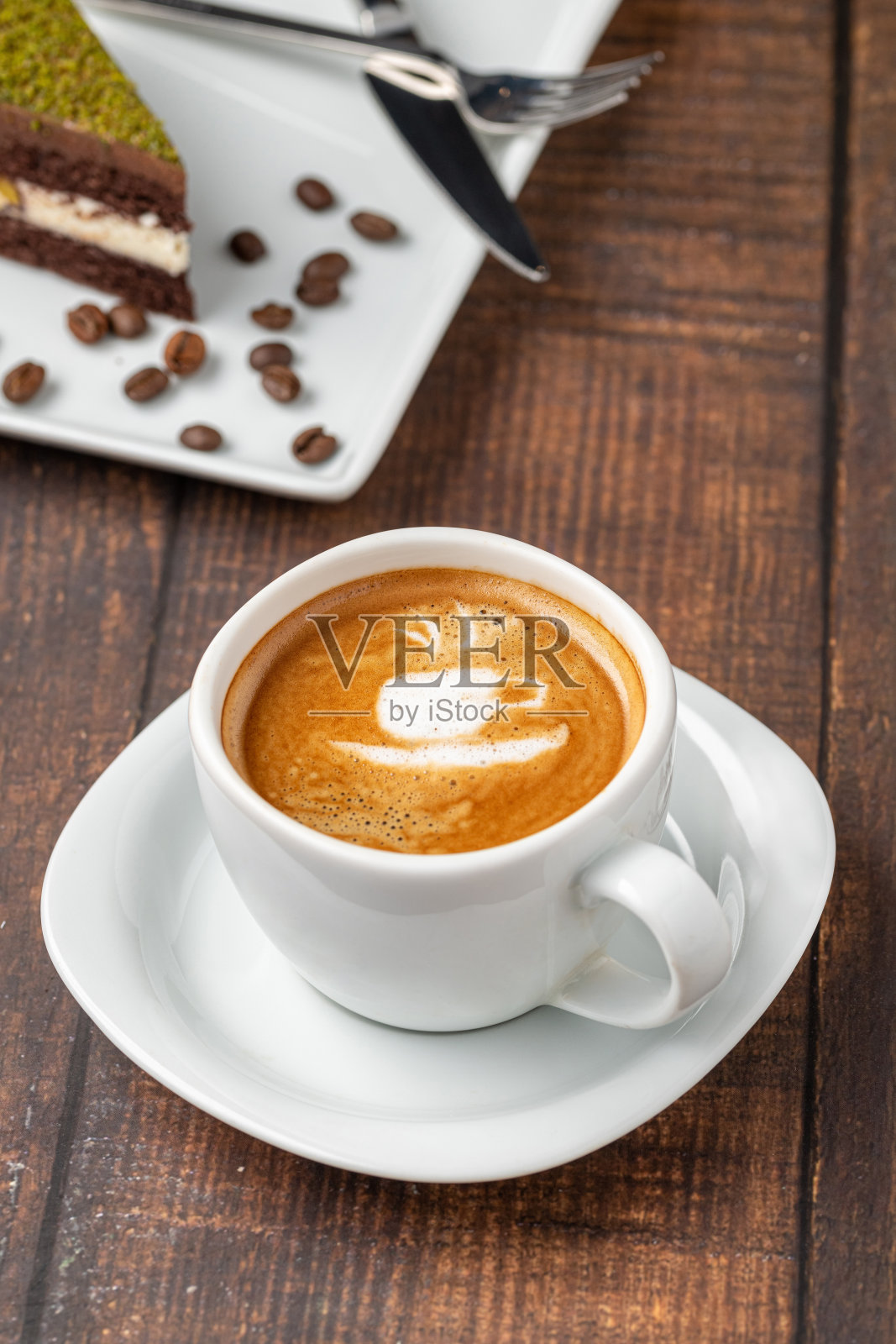 木桌上的白色瓷杯里有图案的卡布奇诺咖啡照片摄影图片