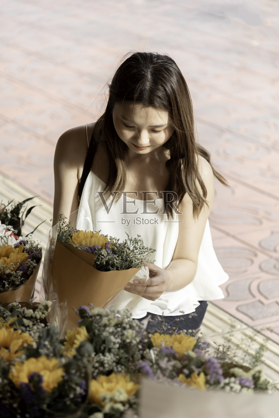 美丽的年轻女子在花店里挑选鲜花。园艺和花卉的概念。照片摄影图片