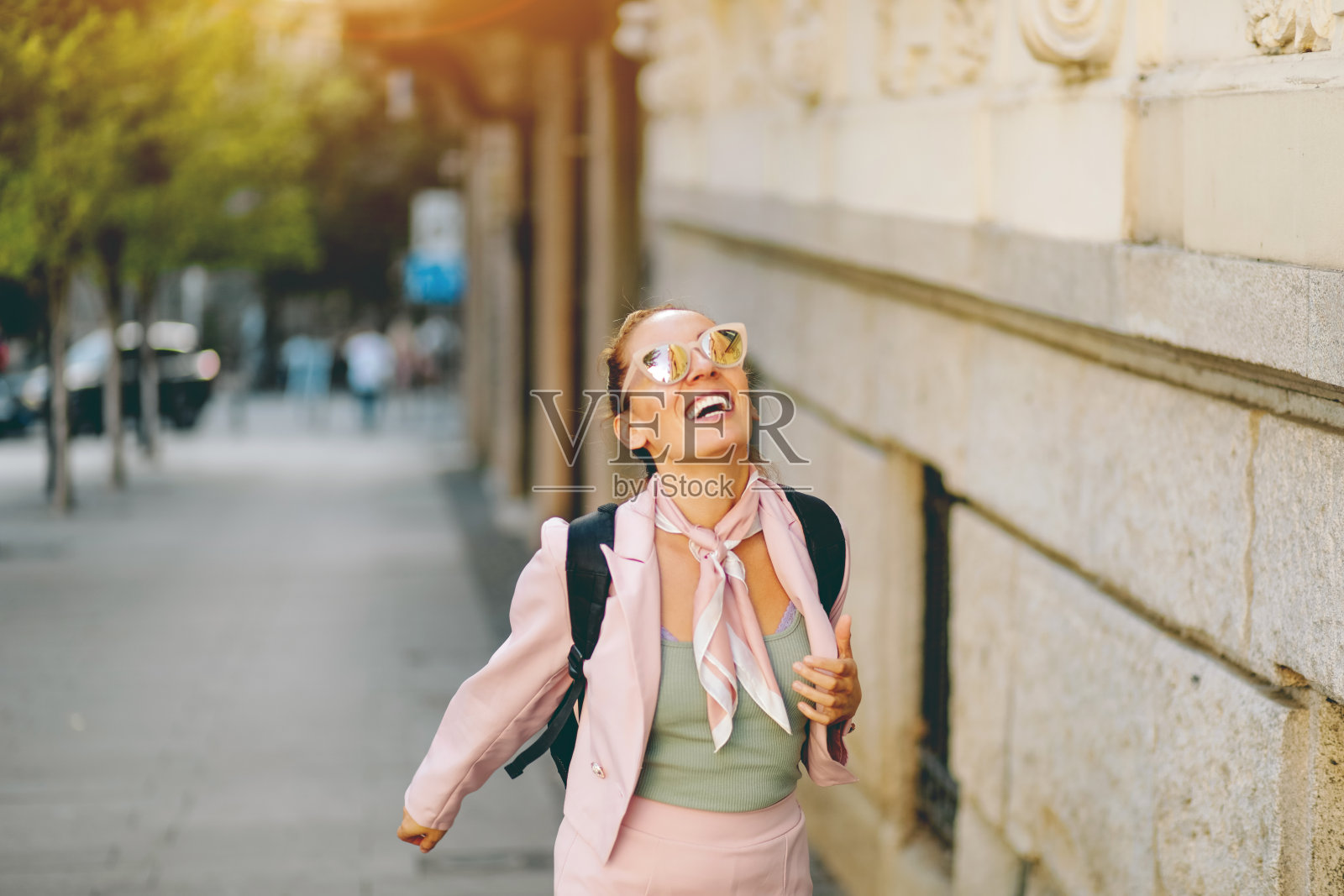 一名女子微笑着走在街上。照片摄影图片