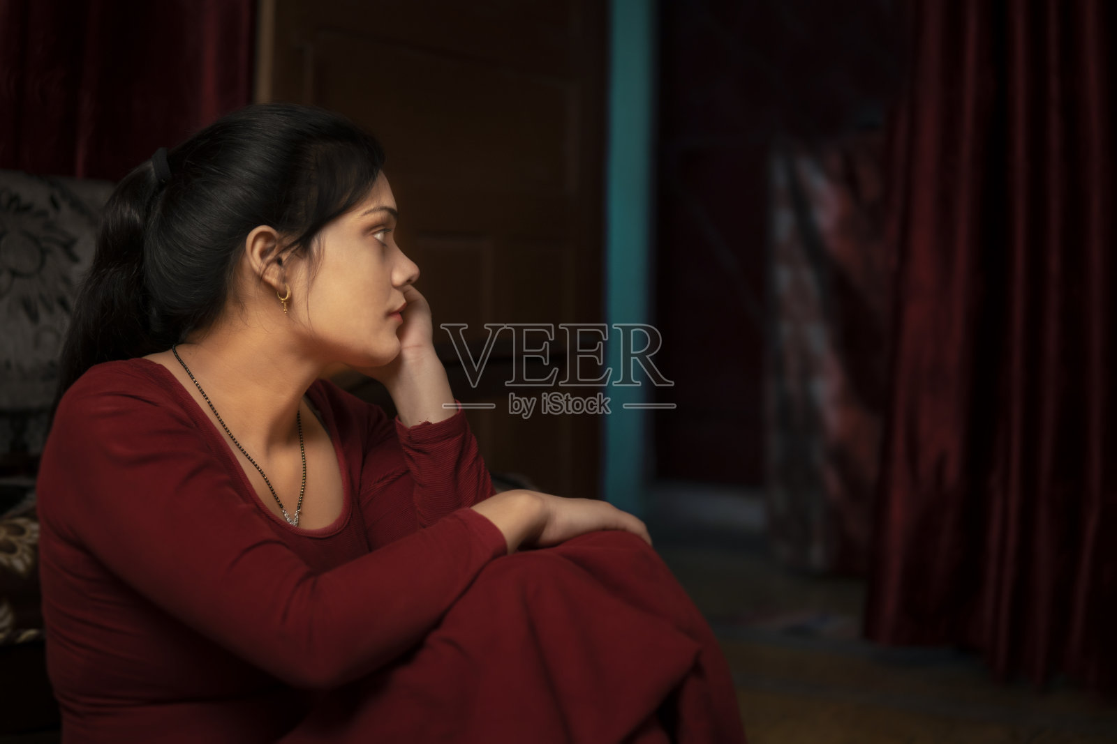 低调的肖像，悲伤，宁静的年轻女子看着门，沉思。照片摄影图片
